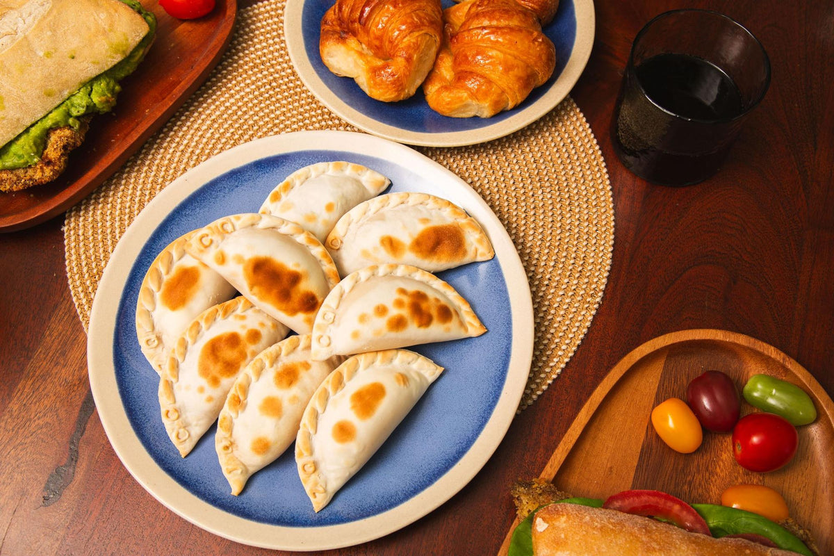 Mesa con empanadas, medialunas y sándwich de milanesa