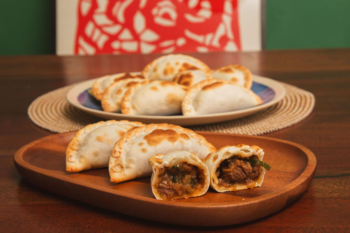 Empanadas de carne recién horneadas, una abierta mostrando el relleno