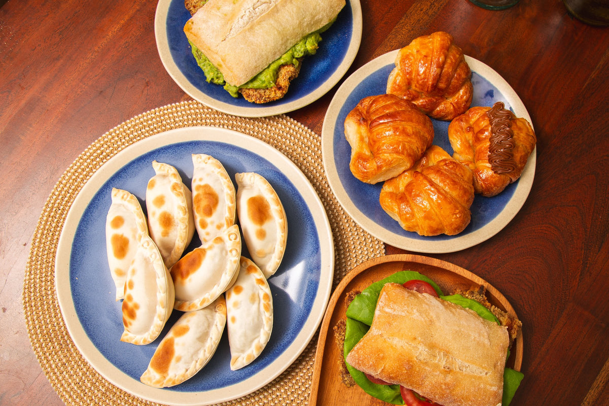 Mesa con empanadas, medialunas y sándwich de milanesa de ChetoMi